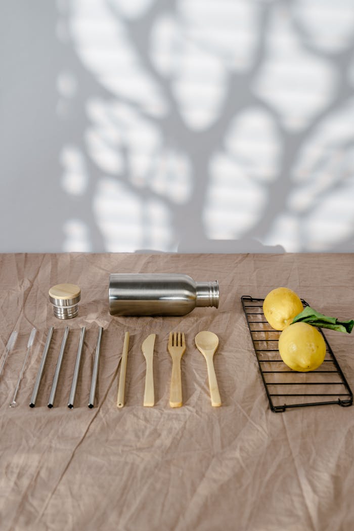 A flat lay of eco-friendly cutlery and lemons on a linen table with soft light and shadows.